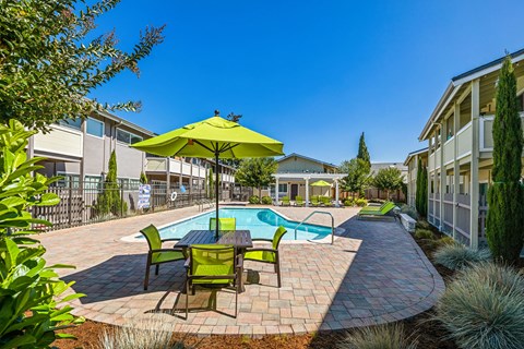 A sunny day at a poolside with a green umbrella.