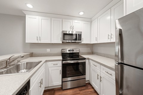 A kitchen with white cabinets and stainless steel appliances.