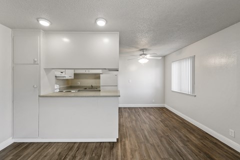 A kitchen with white cabinets and a wooden floor.