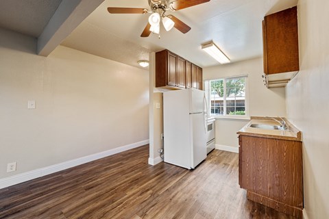 A kitchen with a white refrigerator and wooden floors.