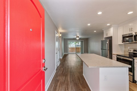 A red door is on the left side of a hallway.