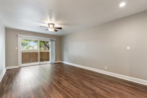 A room with a ceiling fan and sliding glass doors.