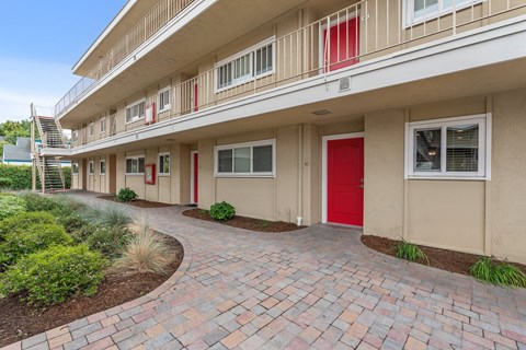 A building with a red door and a brick pathway leading to it.