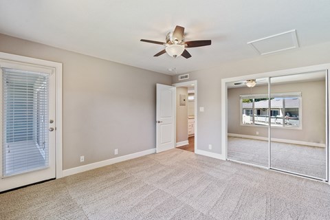 A spacious room with a ceiling fan and sliding glass doors.