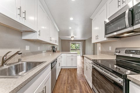 A modern kitchen with white cabinets and stainless steel appliances.