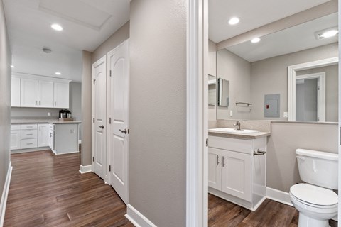 A white toilet is in a bathroom with wood floors.