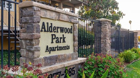 A sign for Alderwood Park Apartments is displayed in front of a building.