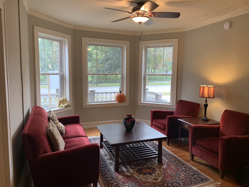 a living room with red furniture and a ceiling fan