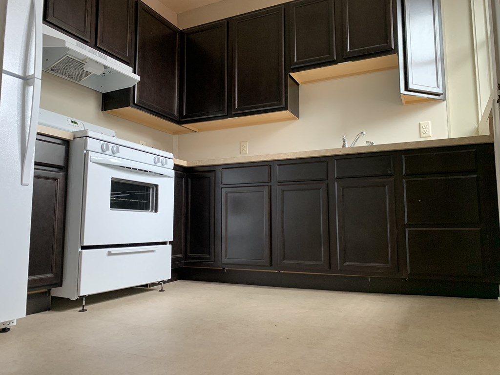 a kitchen with black cabinets and a white stove and refrigerator