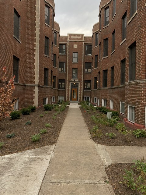 an empty walkway between two brick apartment buildings