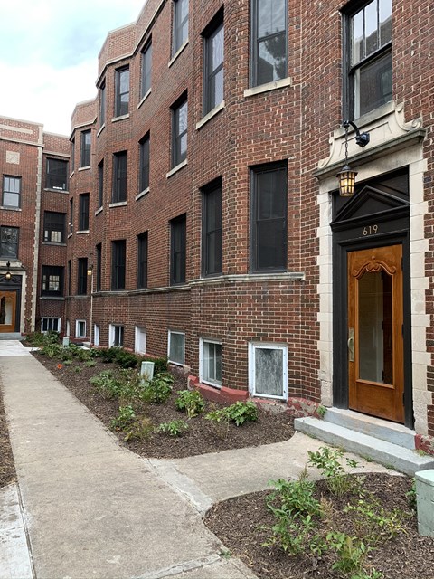 a sidewalk in front of a brick apartment building
