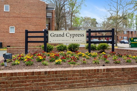 the sign for grand cypress elementary school in front of a brick wall and flowers