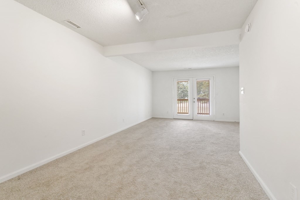 the living room and dining room of an empty home with white walls and carpet