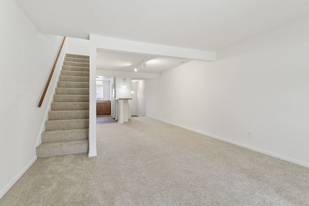 a living room with carpeted stairs and white walls