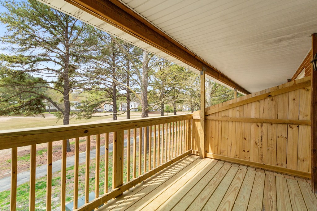 a covered porch with a view of the yard and trees