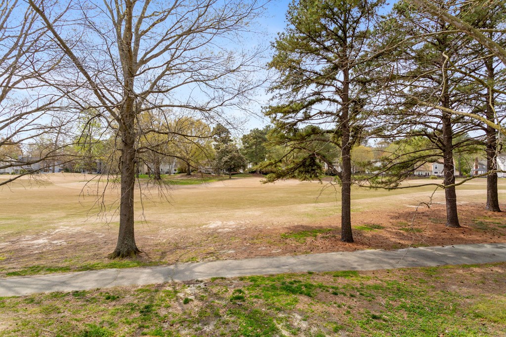 a golf course with trees and a sidewalk