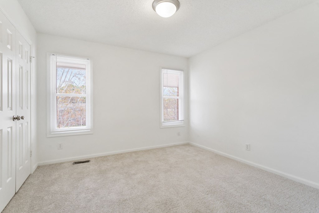 an empty living room with two windows and a door