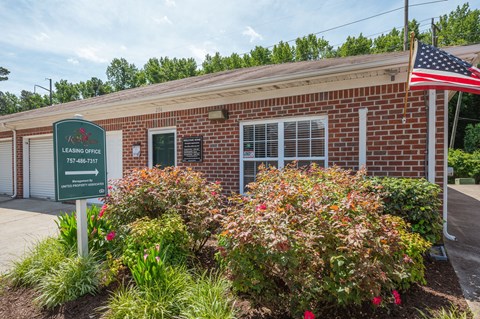 the outside of a brick building with a sign and flowers