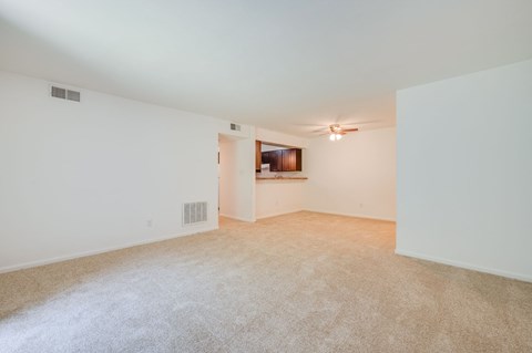 a spacious living room with white walls and carpeting