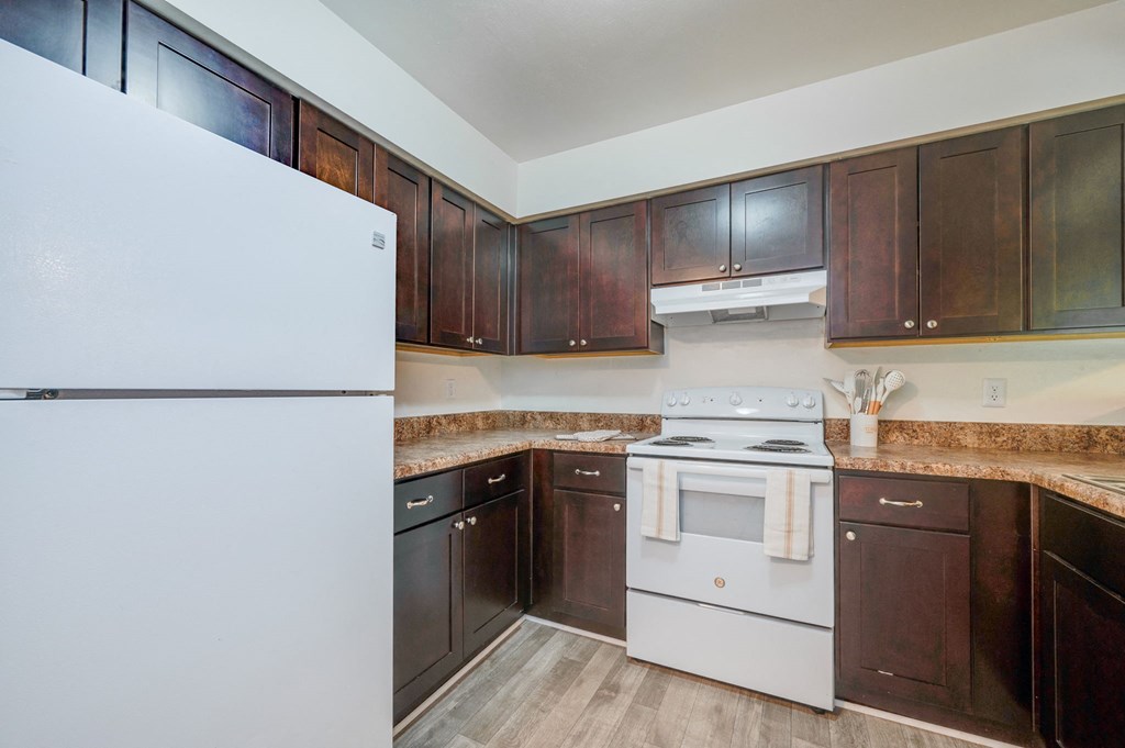 a kitchen with white appliances and dark wood cabinets