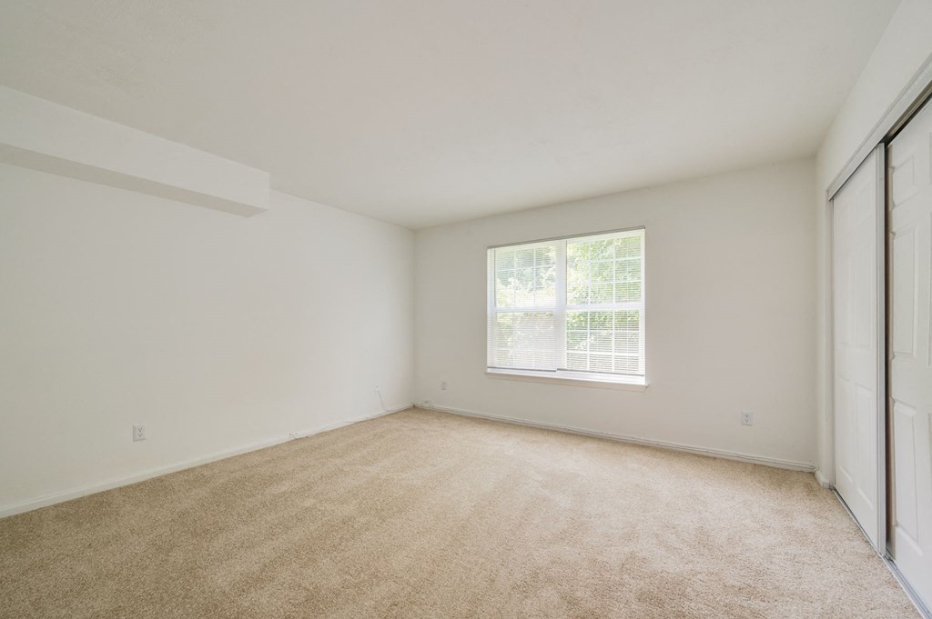 a bedroom with a window and a carpeted floor