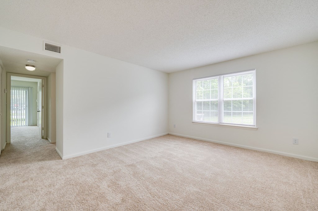 an empty living room with a large window and carpeting