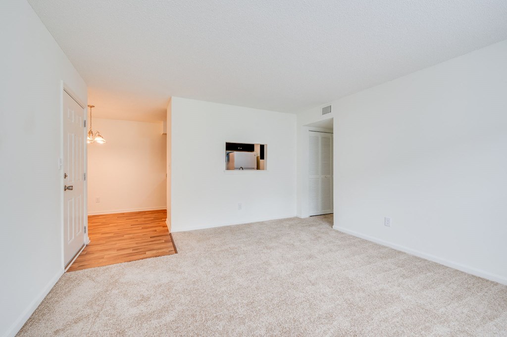 a spacious living room with white walls and a hard wood floor