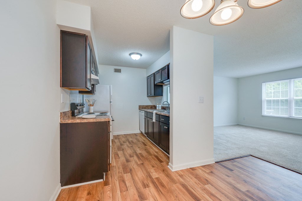 an empty living room and kitchen with a hard wood floor
