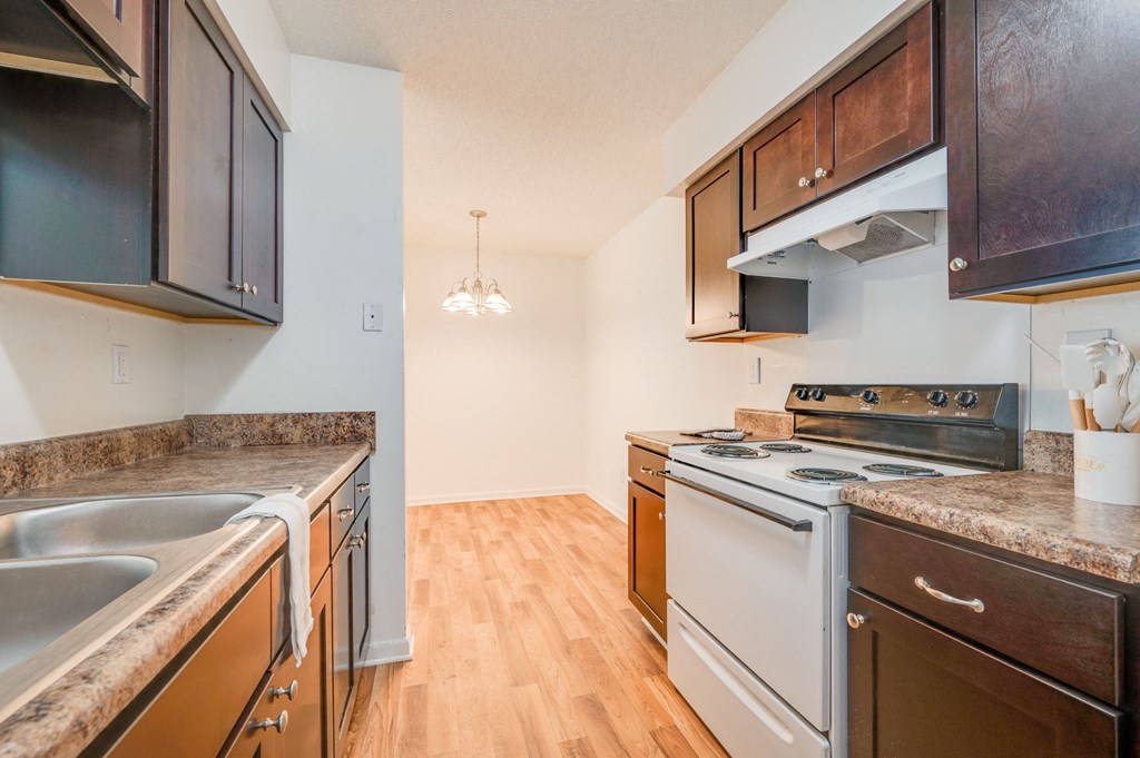 a kitchen with white appliances and wood flooring and wooden cabinets