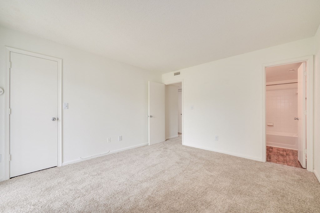 a bedroom with a carpeted floor and a door to a closet