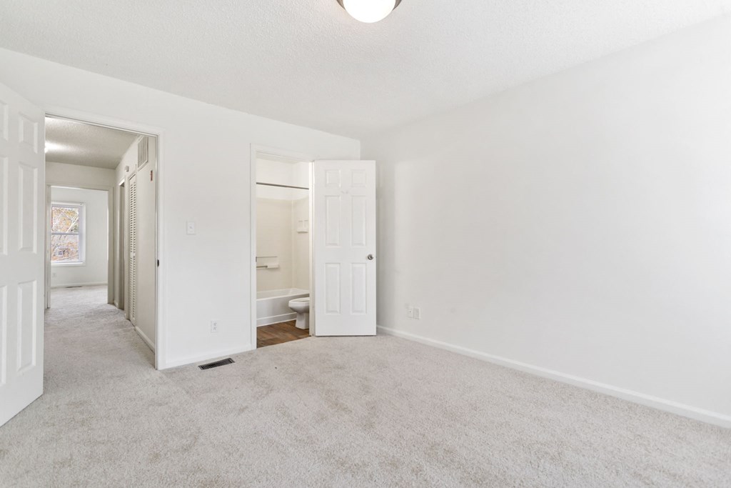an empty living room with white walls and a white door to a bathroom
