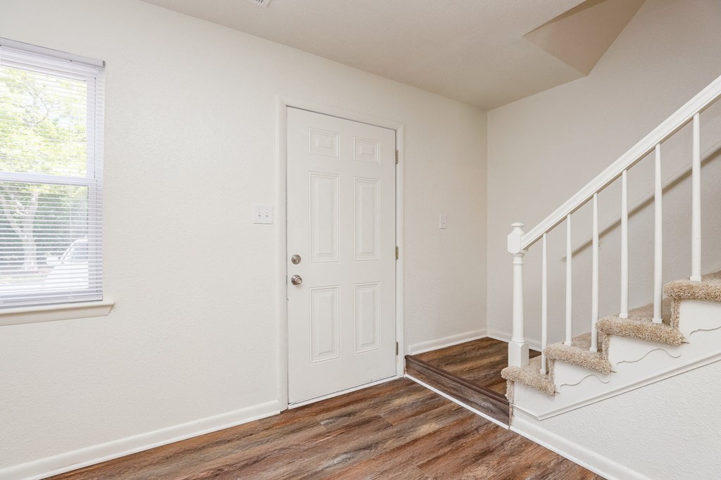 the entrance to a home with stairs and a white door