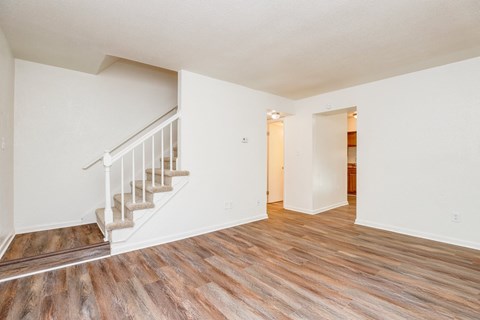 the living room and dining room of a renovated home with wood flooring and stairs