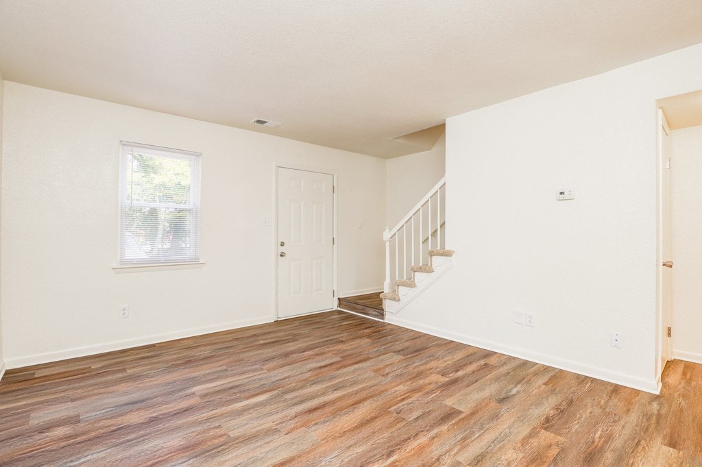 the living room and entry way of a home with carpet and stairs