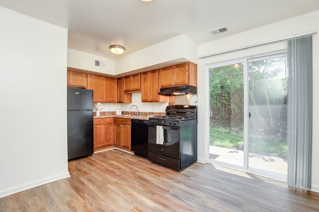 a kitchen with black appliances and wooden cabinets and a sliding glass door