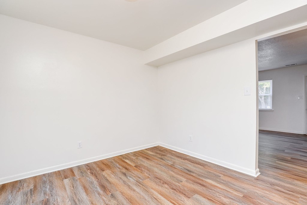 an empty room with white walls and wood floors