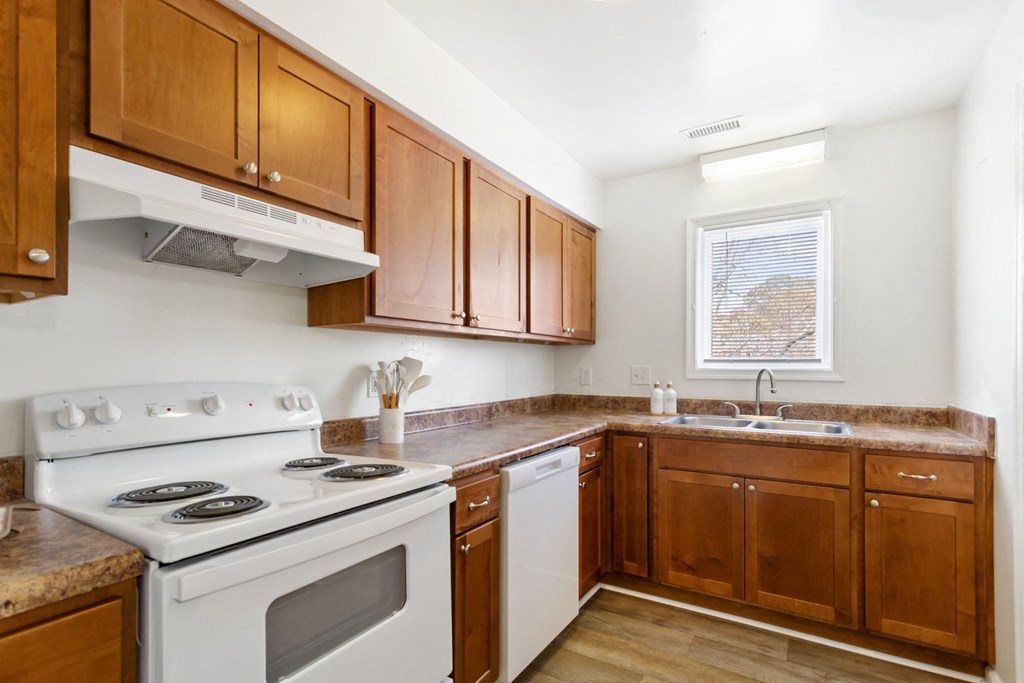 a kitchen with wooden cabinets and white appliances and a stove top oven