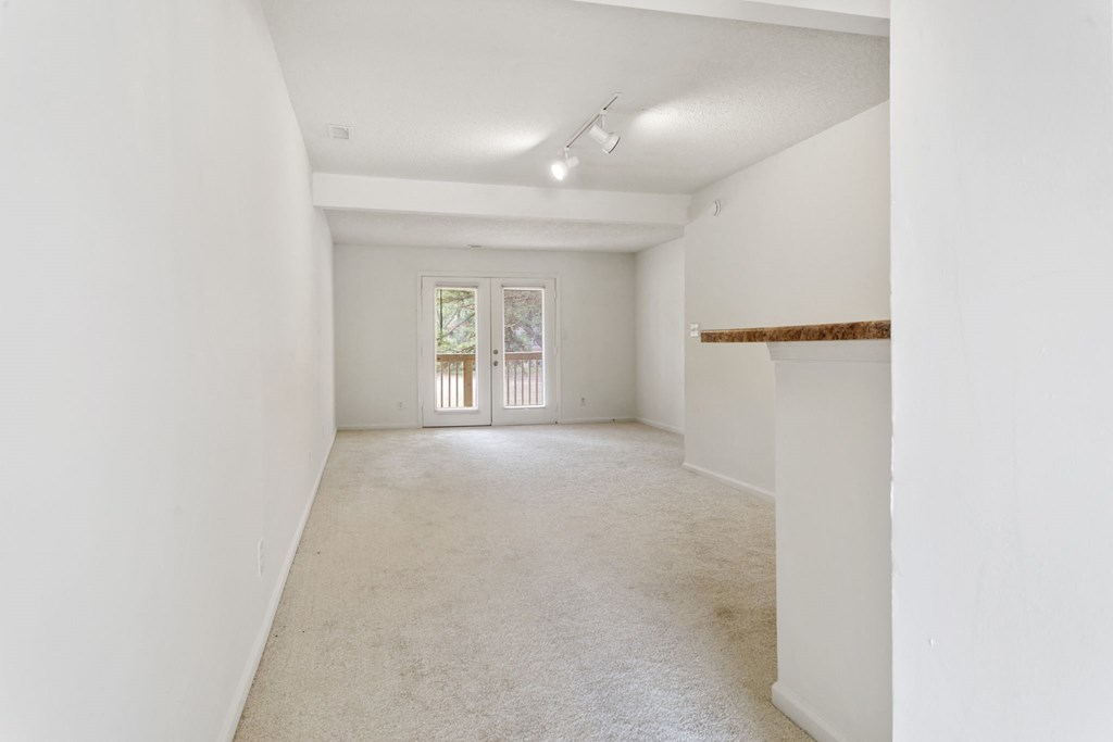 the living room and dining room of an empty home with white walls and white carpet