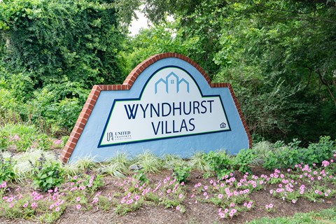 a sign in front of trees and flowers