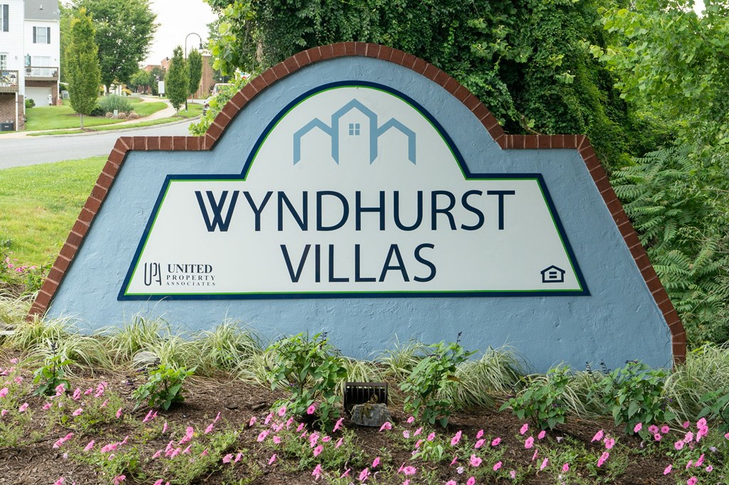 a sign for wynnhurst villas in front of trees and flowers