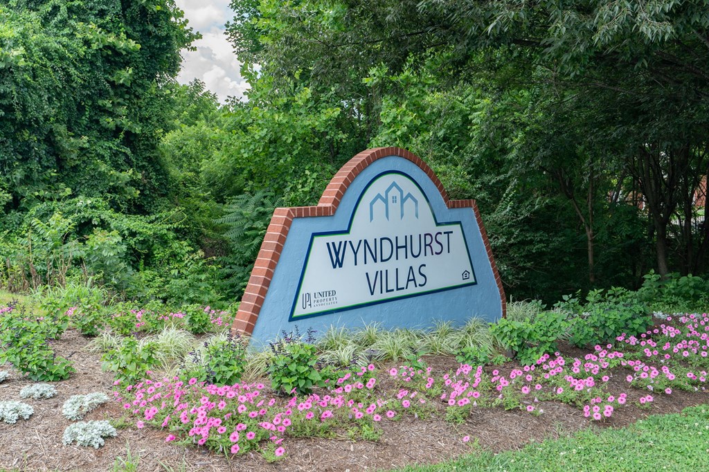 a sign for winthrop villas in front of flowers and trees