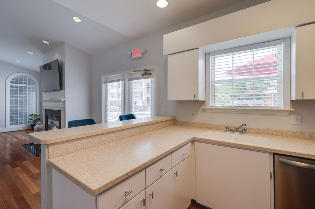 a kitchen with white cabinets and a counter top and a window