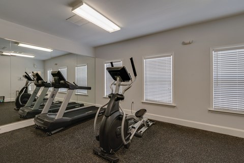 a gym with treadmills and ellipticals at the enclave at woodbridge apartments
