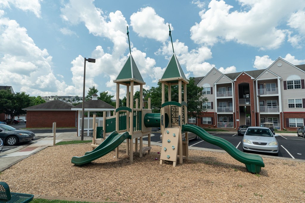 a playground with slides and climbing equipment in front of apartment buildings