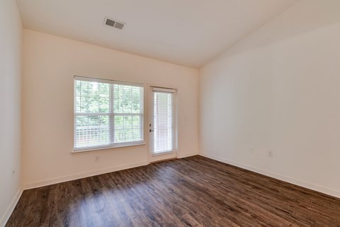 an empty living room with wood floors and a window
