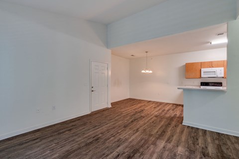 an empty living room with a microwave and a kitchen