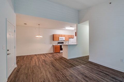a living room and kitchen with wood flooring and white walls