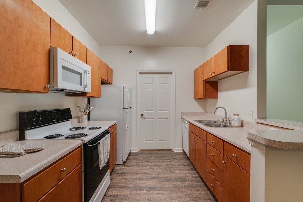 a kitchen with wooden cabinets and white appliances and a white door