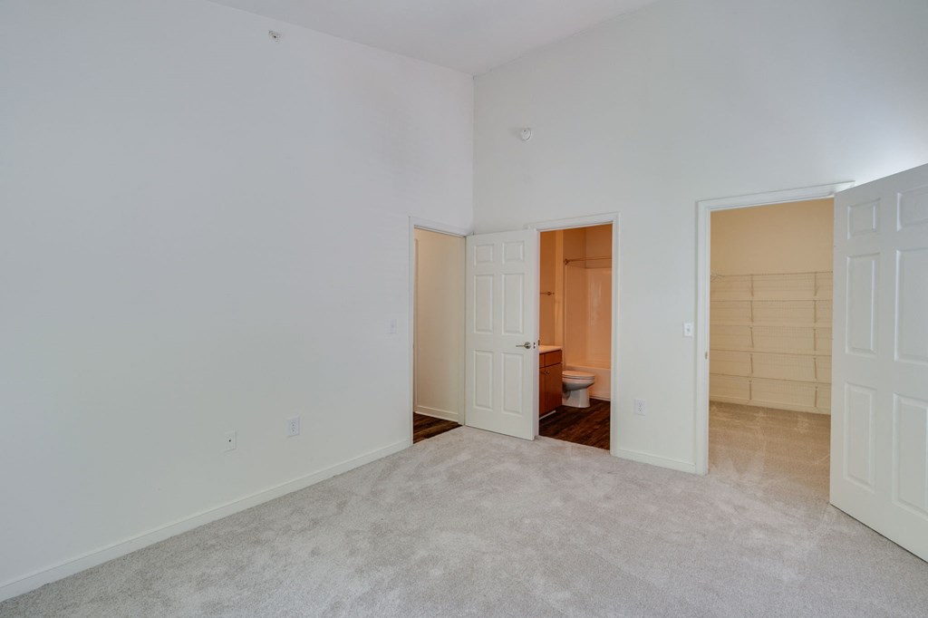 a bedroom with a door to a bathroom and a closet