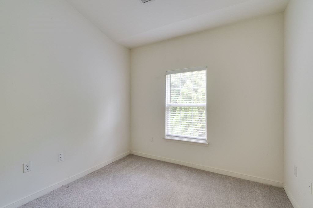 a bedroom with white walls and a window